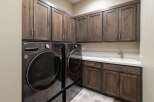 This laundry room boasts ample storage with dark wood cabinetry, both above and below the countertop.
