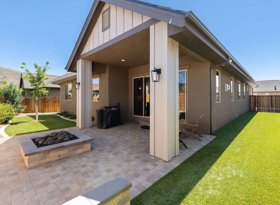 Enjoy outdoor living with this beautifully designed backyard featuring a modern gas fire pit and a spacious paved patio perfect for entertaining.