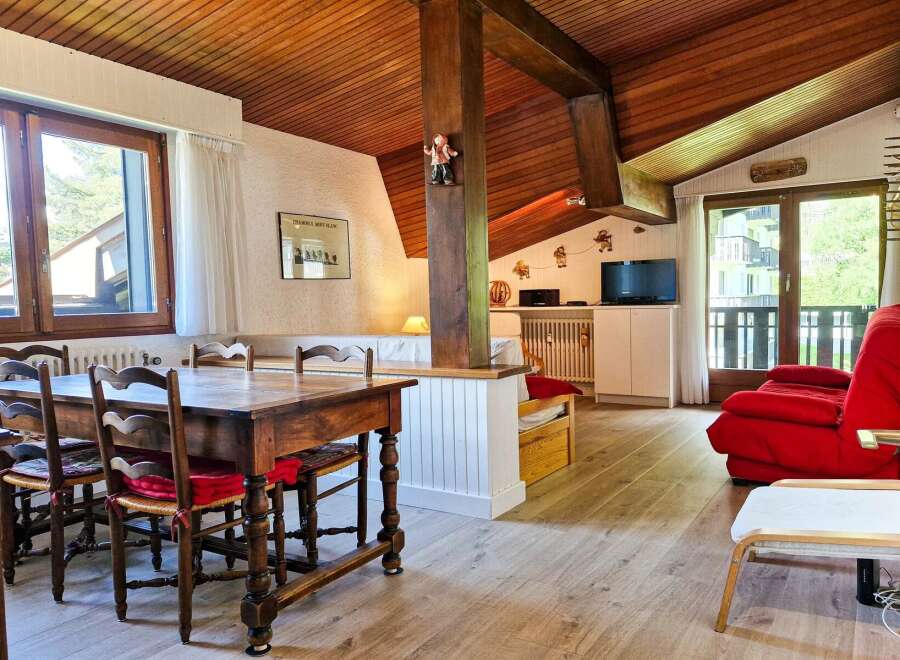 Experience cozy living in this charming mountain retreat, featuring a rustic wooden dining table with four chairs, perfect for family meals.