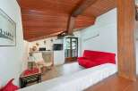 Experience cozy living in this charming room featuring a vibrant red sofa and a comfortable armchair, perfect for relaxation.