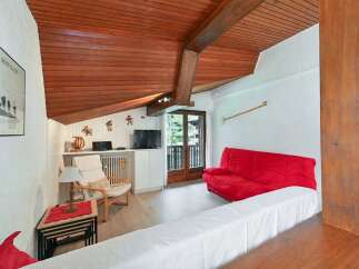 Experience cozy living in this charming room featuring a vibrant red sofa and a comfortable armchair, perfect for relaxation.