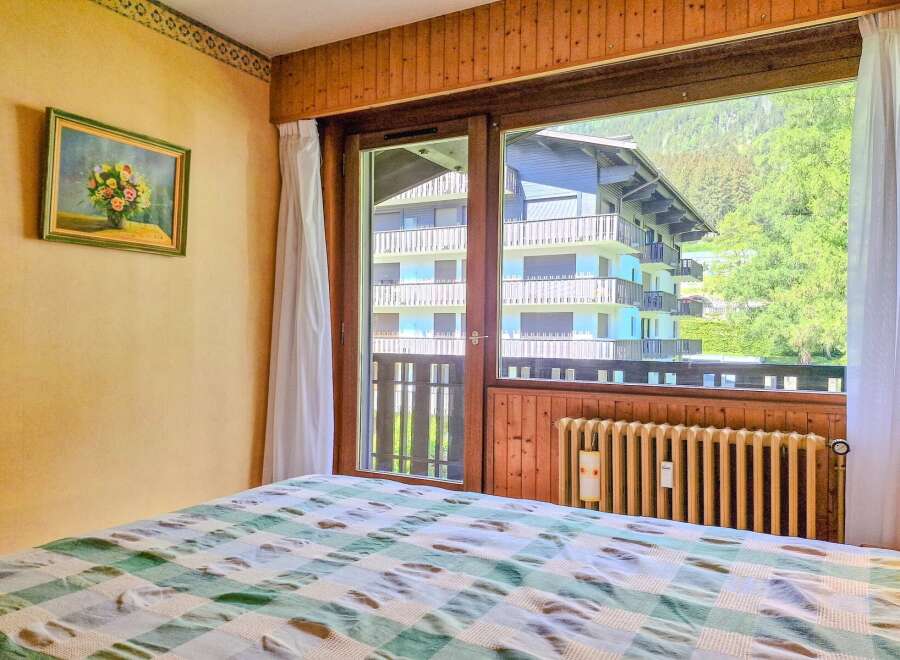 Experience breathtaking mountain views from this charming bedroom, featuring a cozy bed adorned with a classic green and white checkered comforter.