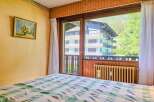 Experience breathtaking mountain views from this charming bedroom, featuring a cozy bed adorned with a classic green and white checkered comforter.