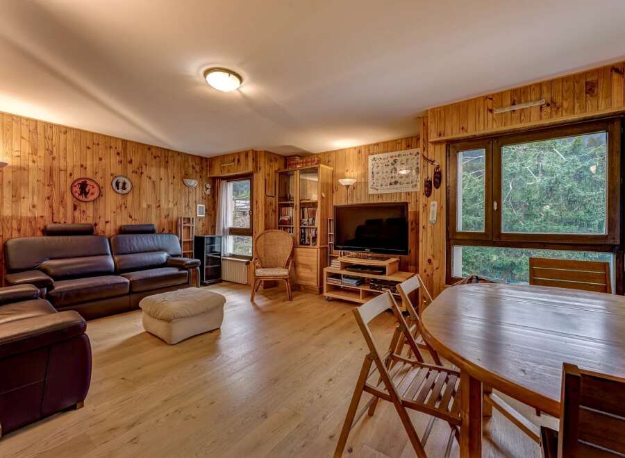 This cozy living room features warm wood-paneled walls and a comfortable leather sofa set, perfect for relaxation.
