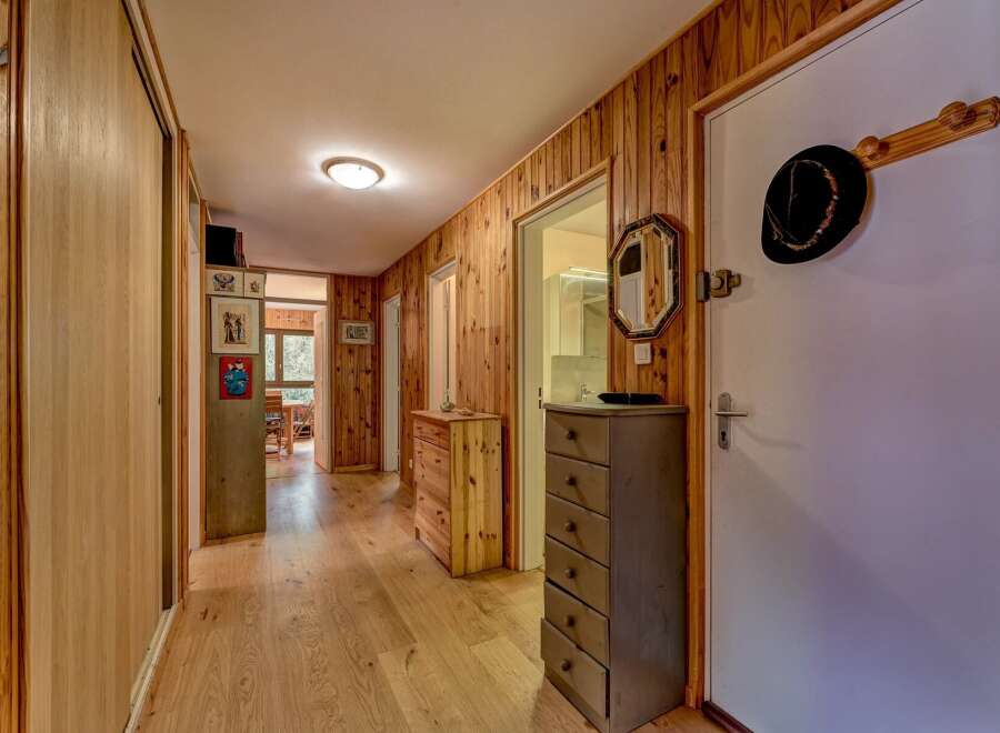 Step into this charming hallway featuring warm wood-paneled walls and a polished hardwood floor, creating a cozy and inviting atmosphere.