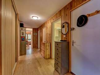 Step into this charming hallway featuring warm wood-paneled walls and a polished hardwood floor, creating a cozy and inviting atmosphere.