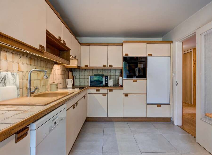 This charming kitchen features a practical layout with ample cabinet space and a built-in oven and microwave.