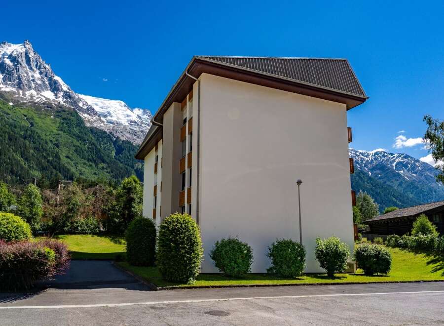 Experience alpine living in this modern building nestled against a backdrop of majestic snow-capped mountains and lush green forests.