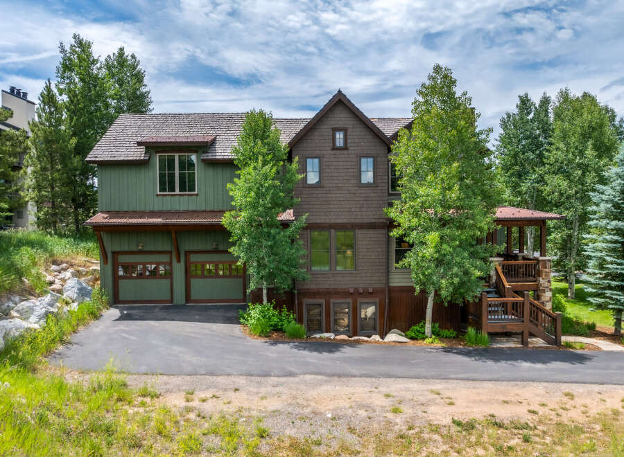 Discover this stunning mountain home featuring a charming green exterior and a rich brown shingle facade, complemented by a rustic wood-shingled roof.