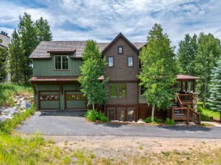 Discover this stunning mountain home featuring a charming green exterior and a rich brown shingle facade, complemented by a rustic wood-shingled roof.