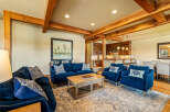 Experience rustic elegance in this spacious living area, featuring exposed wooden beams and a cozy seating arrangement centered around a coffee table.