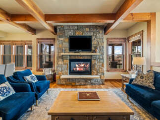 Experience rustic luxury in this stunning living room, featuring a grand stone fireplace as the centerpiece.