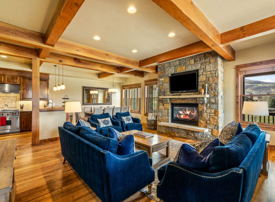 Experience luxurious mountain living in this stunning great room, featuring a grand stone fireplace and exposed wooden beams that add rustic charm.
