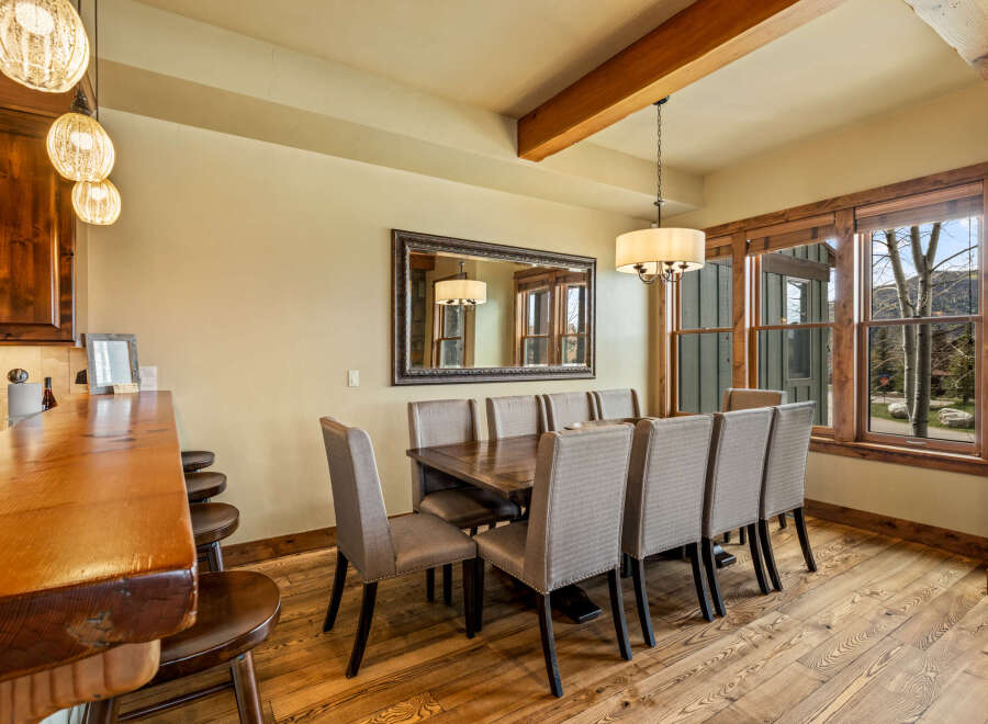 Experience elegant dining in this spacious room, featuring a large wooden table surrounded by upholstered chairs, perfect for hosting gatherings.