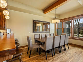 Experience elegant dining in this spacious room, featuring a large wooden table surrounded by upholstered chairs, perfect for hosting gatherings.