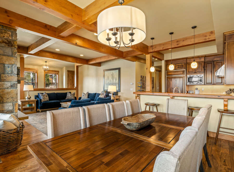 Experience rustic charm and modern comfort in this open-concept living space, featuring a grand stone fireplace and exposed wooden beams.