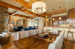 Experience rustic charm and modern comfort in this open-concept living space, featuring a grand stone fireplace and exposed wooden beams.