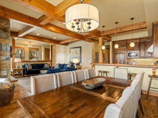 Experience rustic charm and modern comfort in this open-concept living space, featuring a grand stone fireplace and exposed wooden beams.