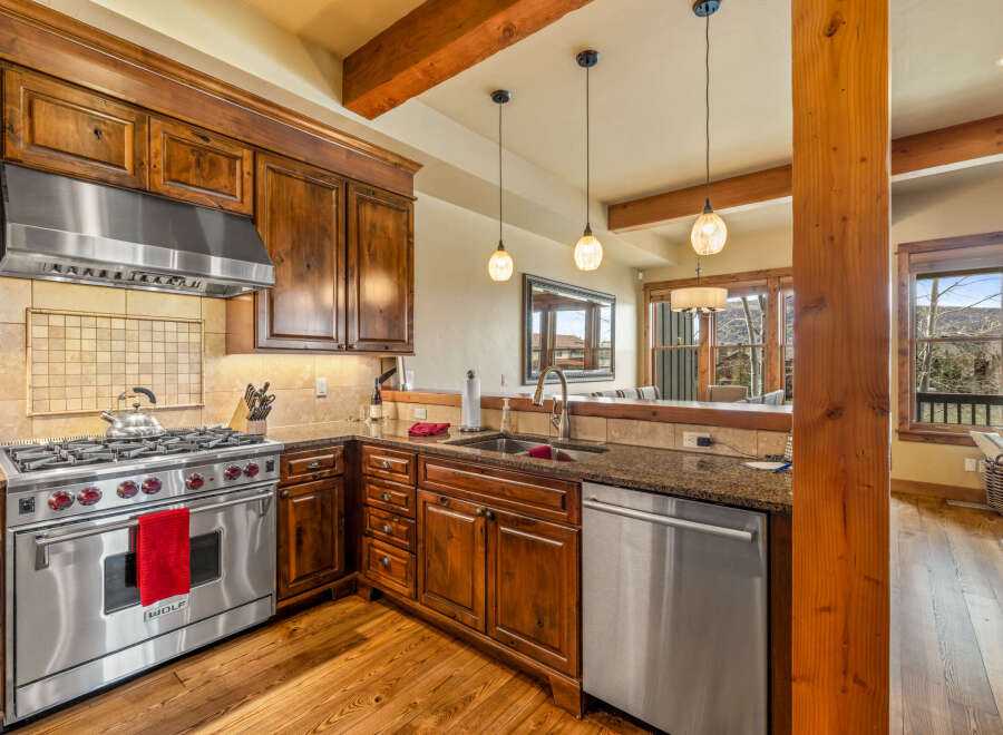 Experience luxury mountain living in this stunning kitchen, featuring rich wood cabinetry, granite countertops, and a professional-grade stainless steel range.