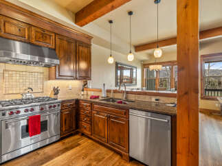 Experience luxury mountain living in this stunning kitchen, featuring rich wood cabinetry, granite countertops, and a professional-grade stainless steel range.