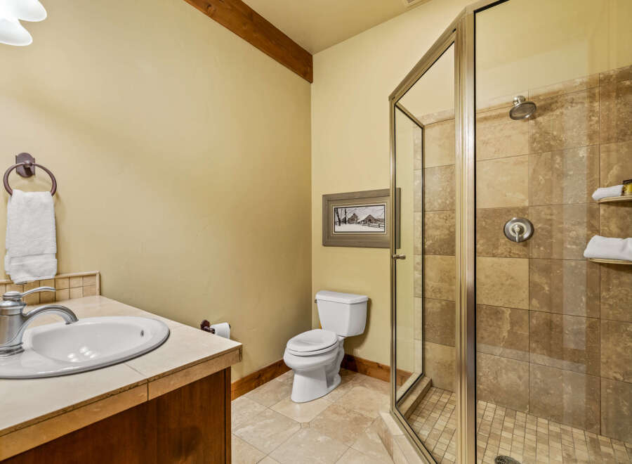 This bathroom features a spacious walk-in shower with elegant tile work and a built-in shelf for toiletries.