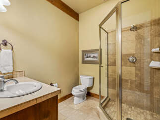 This bathroom features a spacious walk-in shower with elegant tile work and a built-in shelf for toiletries.