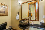 This powder room features a unique stone vessel sink atop a live-edge granite vanity, complemented by a polished chrome faucet.