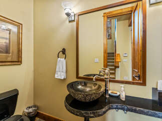 This powder room features a unique stone vessel sink atop a live-edge granite vanity, complemented by a polished chrome faucet.