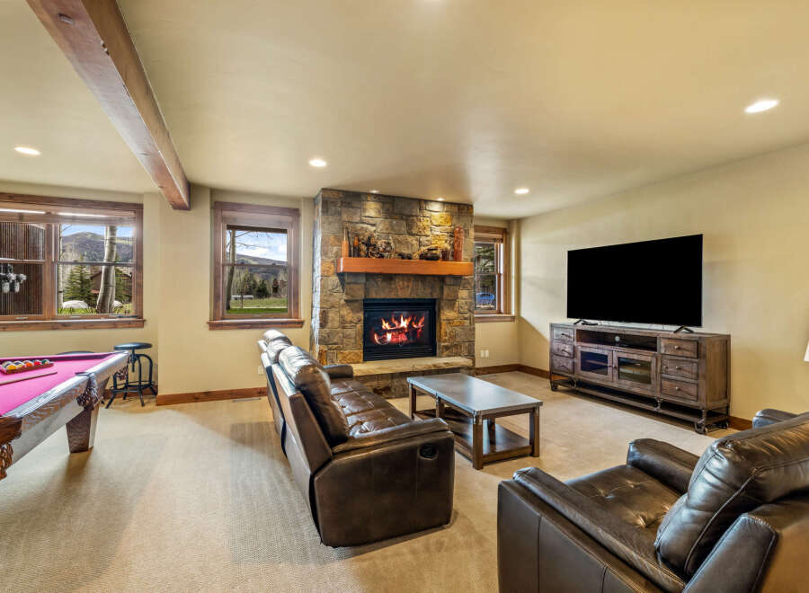 Experience ultimate relaxation in this cozy basement living area, featuring a stone fireplace and plush leather seating.
