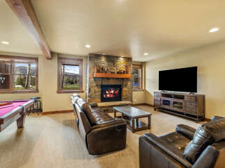 Experience ultimate relaxation in this cozy basement living area, featuring a stone fireplace and plush leather seating.