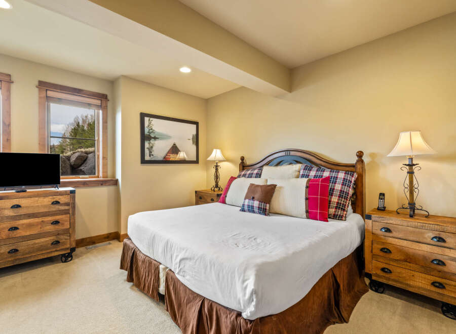 Experience rustic charm in this inviting bedroom, featuring a comfortable king-size bed adorned with plush pillows and a cozy plaid comforter.