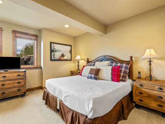 Experience rustic charm in this inviting bedroom, featuring a comfortable king-size bed adorned with plush pillows and a cozy plaid comforter.
