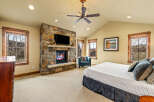 Experience ultimate comfort in this luxurious bedroom, featuring a stunning stone fireplace with a mounted television for cozy evenings.