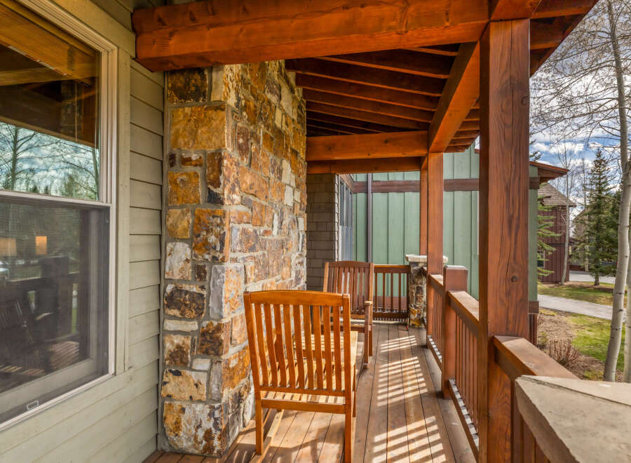 Enjoy the crisp mountain air from this charming covered porch, featuring rustic stone accents and warm wooden beams.