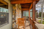 Enjoy the crisp mountain air from this charming covered porch, featuring rustic stone accents and warm wooden beams.