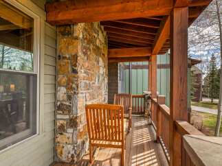 Enjoy the crisp mountain air from this charming covered porch, featuring rustic stone accents and warm wooden beams.