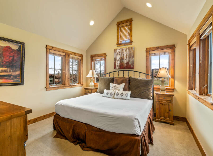 Experience rustic charm in this inviting bedroom, featuring a spacious king-sized bed adorned with plush pillows and a rich brown bed skirt.