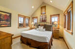 Experience rustic charm in this inviting bedroom, featuring a spacious king-sized bed adorned with plush pillows and a rich brown bed skirt.