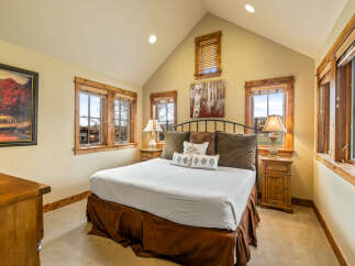 Experience rustic charm in this inviting bedroom, featuring a spacious king-sized bed adorned with plush pillows and a rich brown bed skirt.