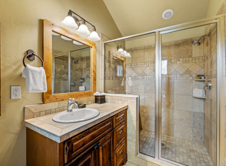 This beautifully appointed bathroom features a spacious walk-in shower with elegant tilework and a glass enclosure.