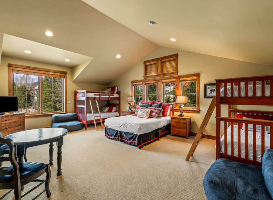 This spacious bedroom offers comfortable sleeping arrangements for multiple guests with two bunk beds and a queen-size bed.
