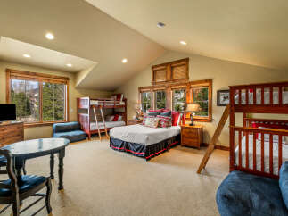 This spacious bedroom offers comfortable sleeping arrangements for multiple guests with two bunk beds and a queen-size bed.