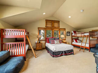 This spacious bedroom is perfect for families or groups, featuring two sturdy wooden bunk beds and a comfortable queen-size bed.