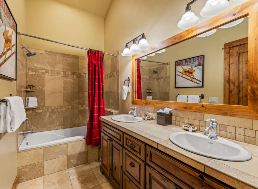This charming bathroom features a spacious bathtub with a red checkered shower curtain, perfect for a relaxing soak.