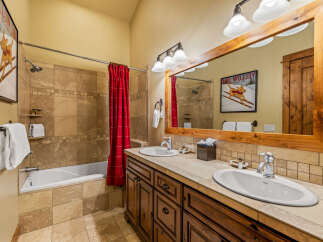 This charming bathroom features a spacious bathtub with a red checkered shower curtain, perfect for a relaxing soak.