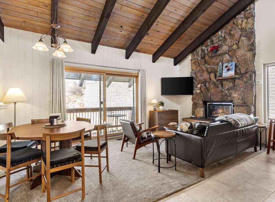 Experience cozy living in this charming mountain retreat, featuring a striking stone fireplace and a vaulted wood-beamed ceiling.
