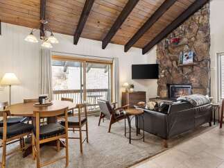 Experience cozy living in this charming mountain retreat, featuring a striking stone fireplace and a vaulted wood-beamed ceiling.