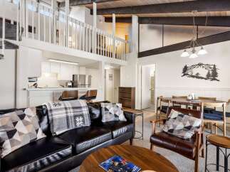 Experience modern living in this stunning loft-style condo, featuring a sleek black leather sofa and a cozy armchair perfect for relaxation.