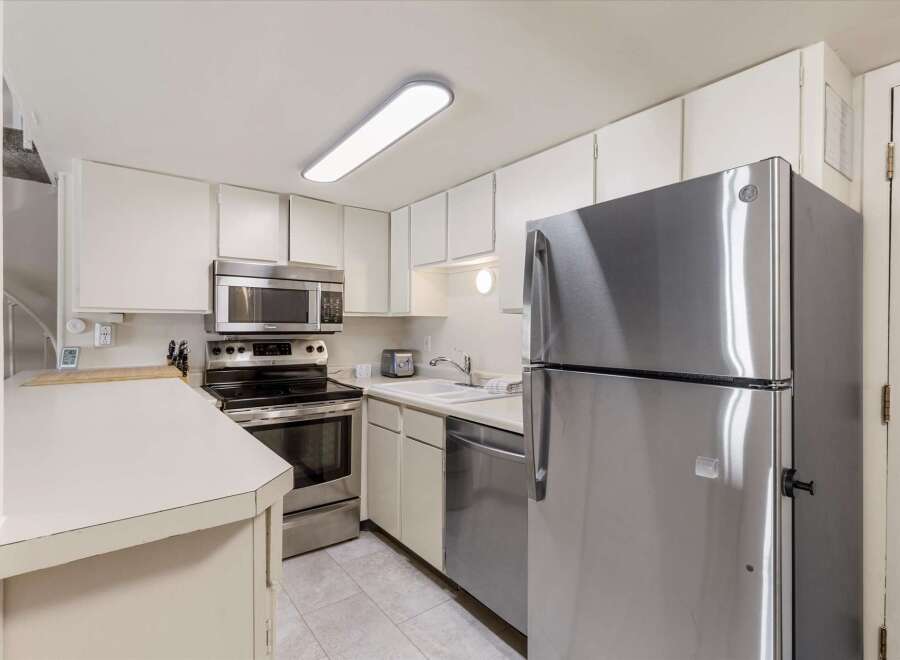 Discover this charming kitchen featuring sleek stainless steel appliances, including a modern refrigerator and a built-in microwave above the stove.
