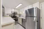 Discover this charming kitchen featuring sleek stainless steel appliances, including a modern refrigerator and a built-in microwave above the stove.
